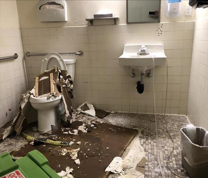 Ceiling piles of tile scattered over bathroom sink and toilet