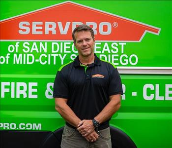 Man standing in front of green wall with SERVPRO logo. 