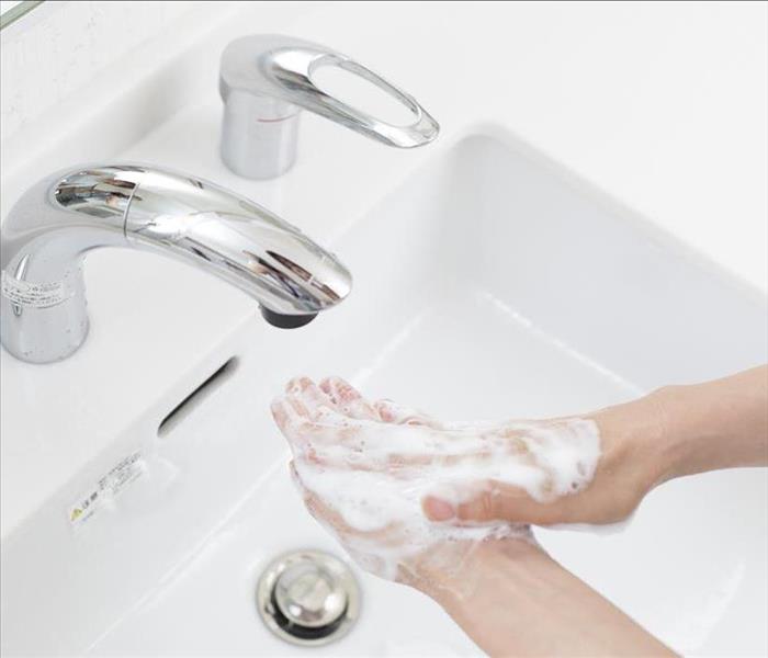 Hands with soap washing on free faucet