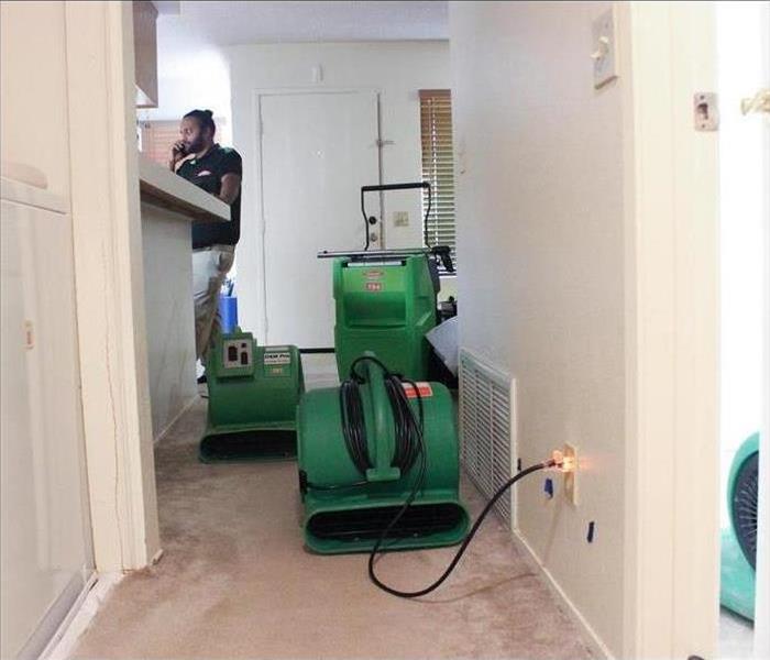 Servpro technician on the phone, while drying equipment is placed inside a home.
